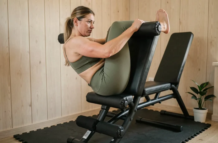 Femme réalisant des relevés de genoux sur chaise romaine dans une salle de sport à domicile pour travailler la sangle abdominale